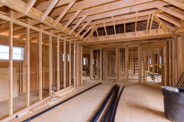 Wooden under construction new residential home beam framing and PVC plastic drain pipe